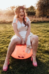 Bride wearing a flower crown in a two piece skirt and top, bouncing on a space hopper