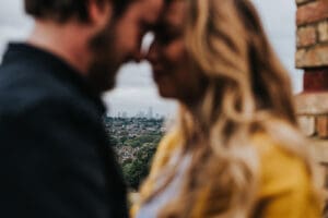 Couple hugging with London skyline behind them, alternative wedding photography.
